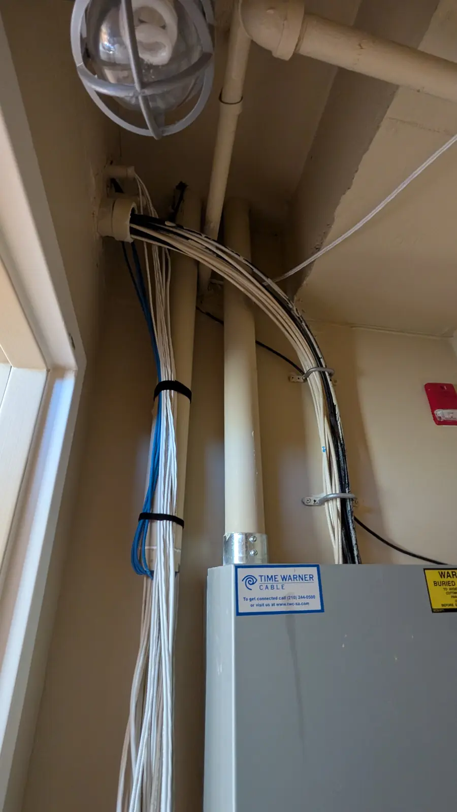 Bundled data cables secured with blue velcro straps running down to an electrical room panel