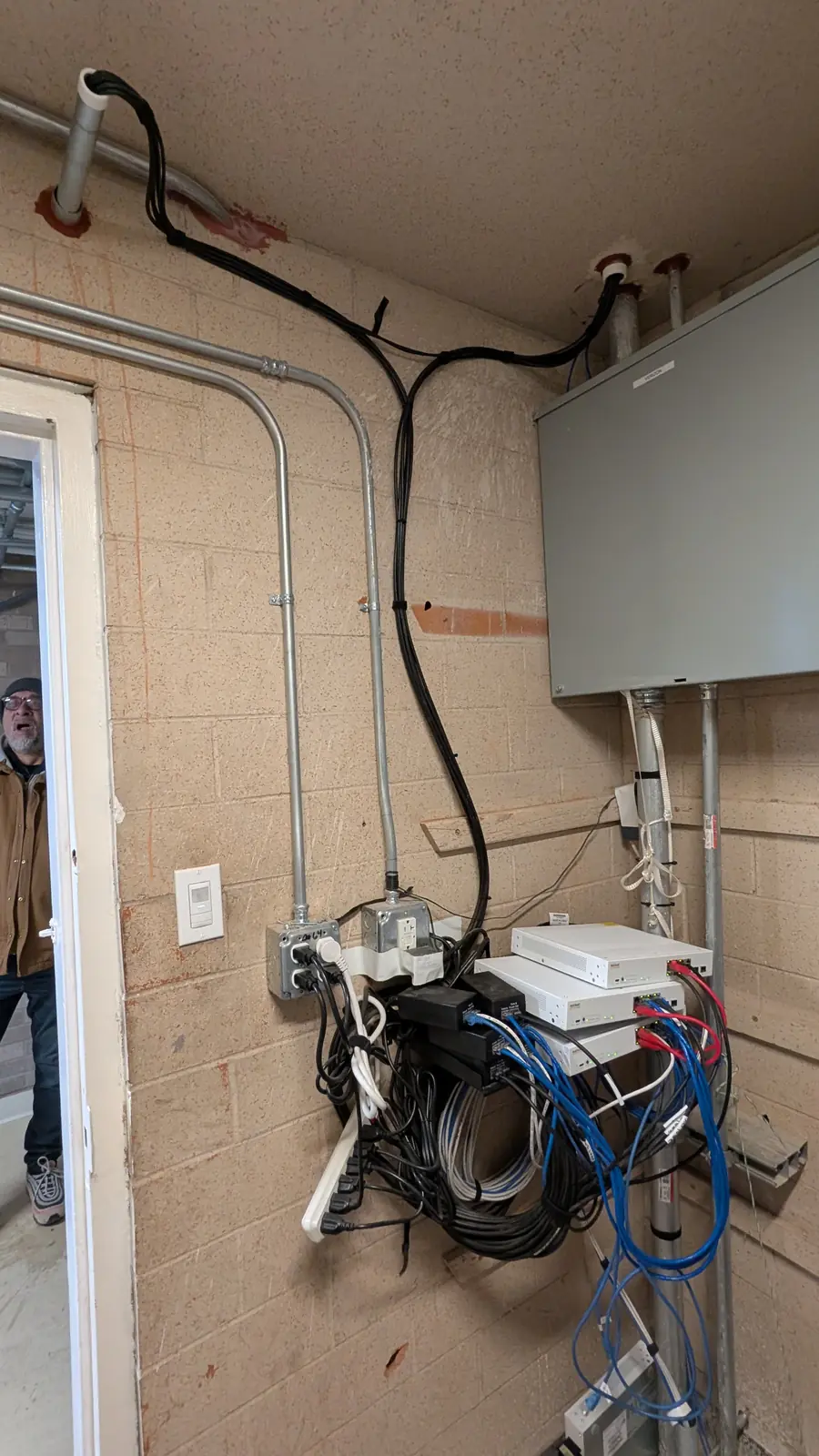 Data cabling and conduit routed along a block wall in a utility room