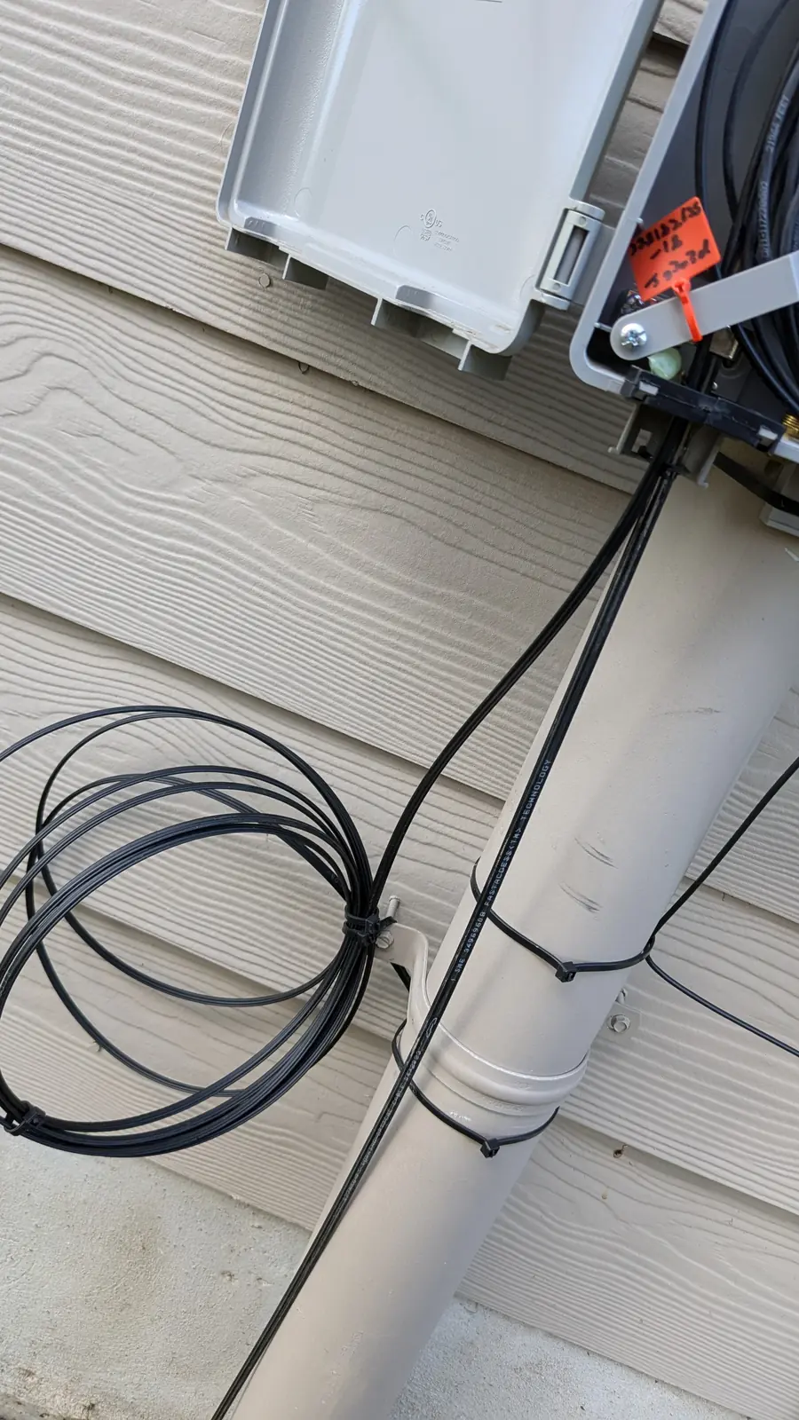 Outdoor fiber drop cable routed down the exterior wall into a weatherproof fiber enclosure