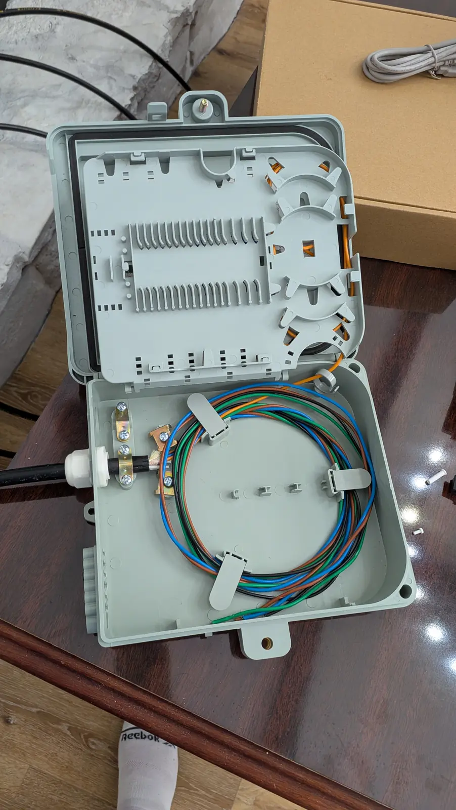Open fiber distribution enclosure with splice tray and color-coded fiber strands routed inside