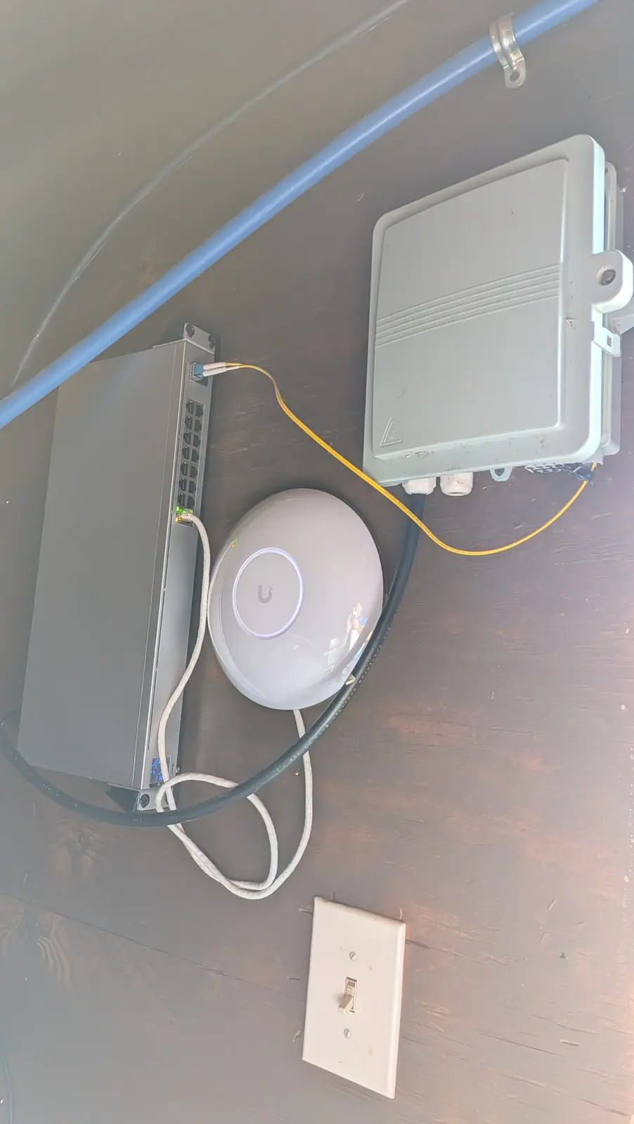 Wireless access point mounted on a wall beside a weatherproof network enclosure